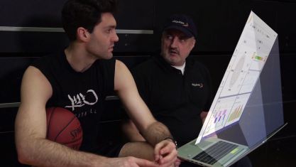 Ein Basketballer und ein Berater sehen sich Trainingsdaten auf einem Laptop an